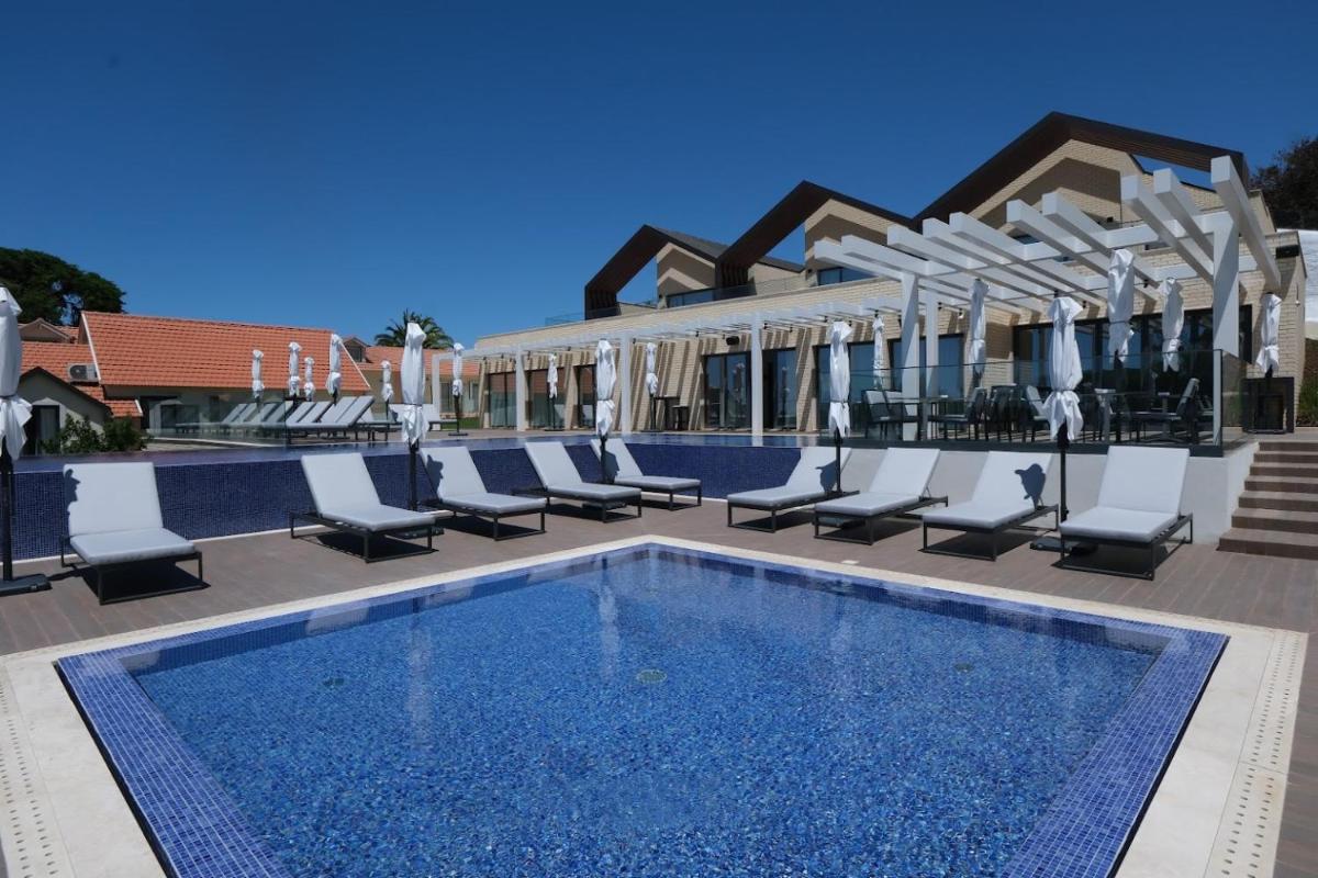 uma piscina com espreguiçadeiras ao lado de um prédio em Quinta da Maquia Hotel em Sintra uma piscina com espreguiçadeiras ao lado de um prédio em Quinta da Maquia Hotel em Sintra