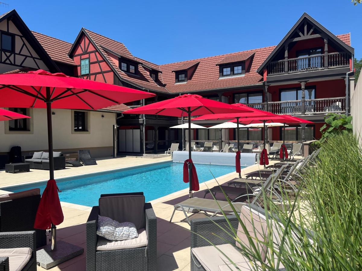 - une piscine avec des parasols rouges et des chaises longues dans l'établissement Au Soleil, Hôtel Restaurant & Spa, à Valff