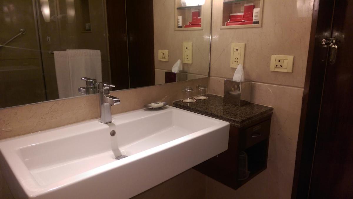 a bathroom with a sink and a large mirror at Vivanta Bengaluru Residency Road in Bengaluru a bathroom with a sink and a large mirror at Vivanta Bengaluru Residency Road in Bengaluru