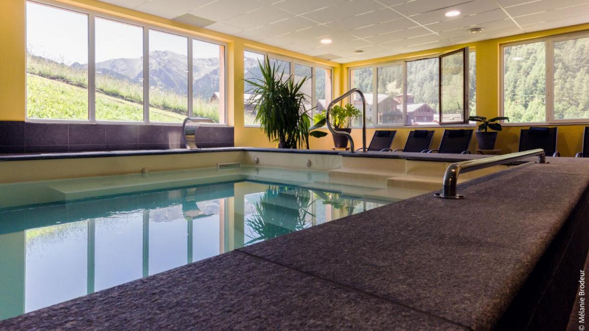 - une piscine dans un bâtiment avec des chaises et des fenêtres dans l'établissement Hotel Spa L'Equipe, à Molines-en-Queyras