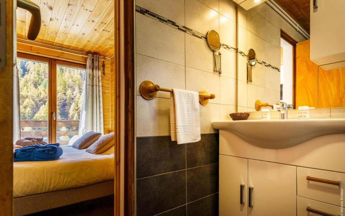 une salle de bain avec un lit, un lavabo et un miroir dans l'établissement Hotel Spa L'Equipe, à Molines-en-Queyras 64 autres photos
