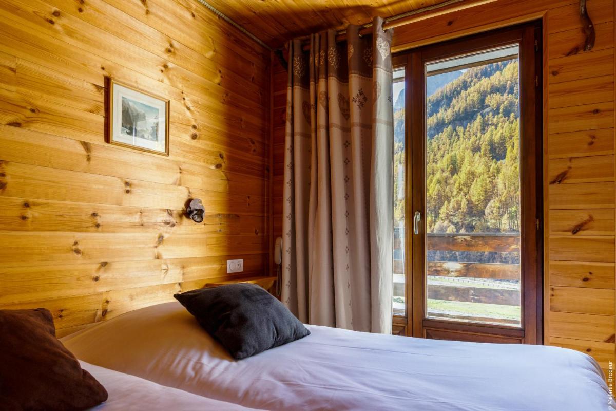 une chambre avec un lit et une grande fenêtre dans l'établissement Hotel Spa L'Equipe, à Molines-en-Queyras