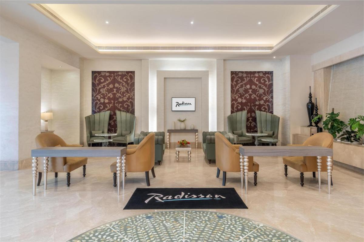 a lobby with two tables and chairs in a building at Radisson Hyderabad Hitec City in Hyderabad