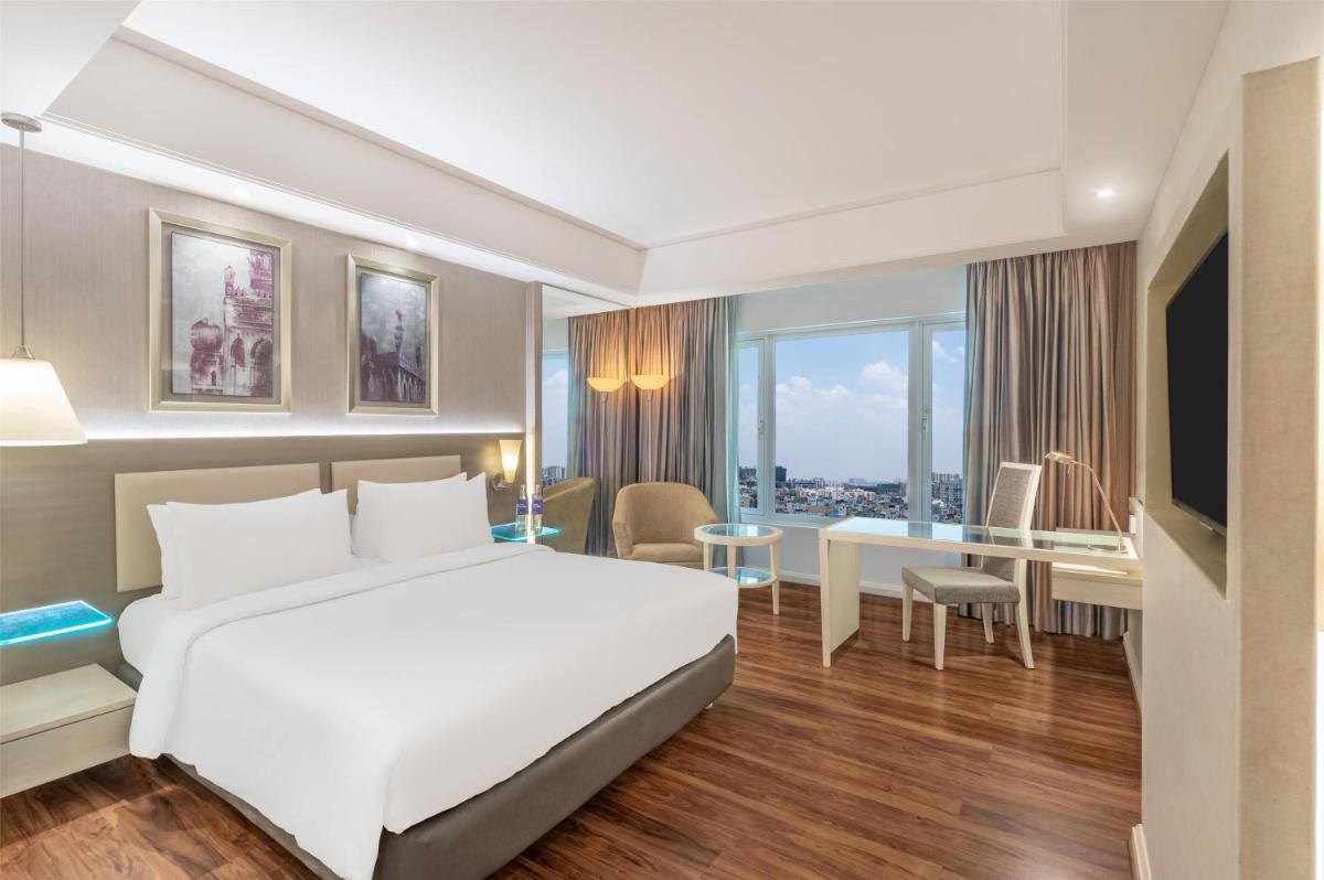 a hotel room with a white bed and a desk at Radisson Hyderabad Hitec City in Hyderabad