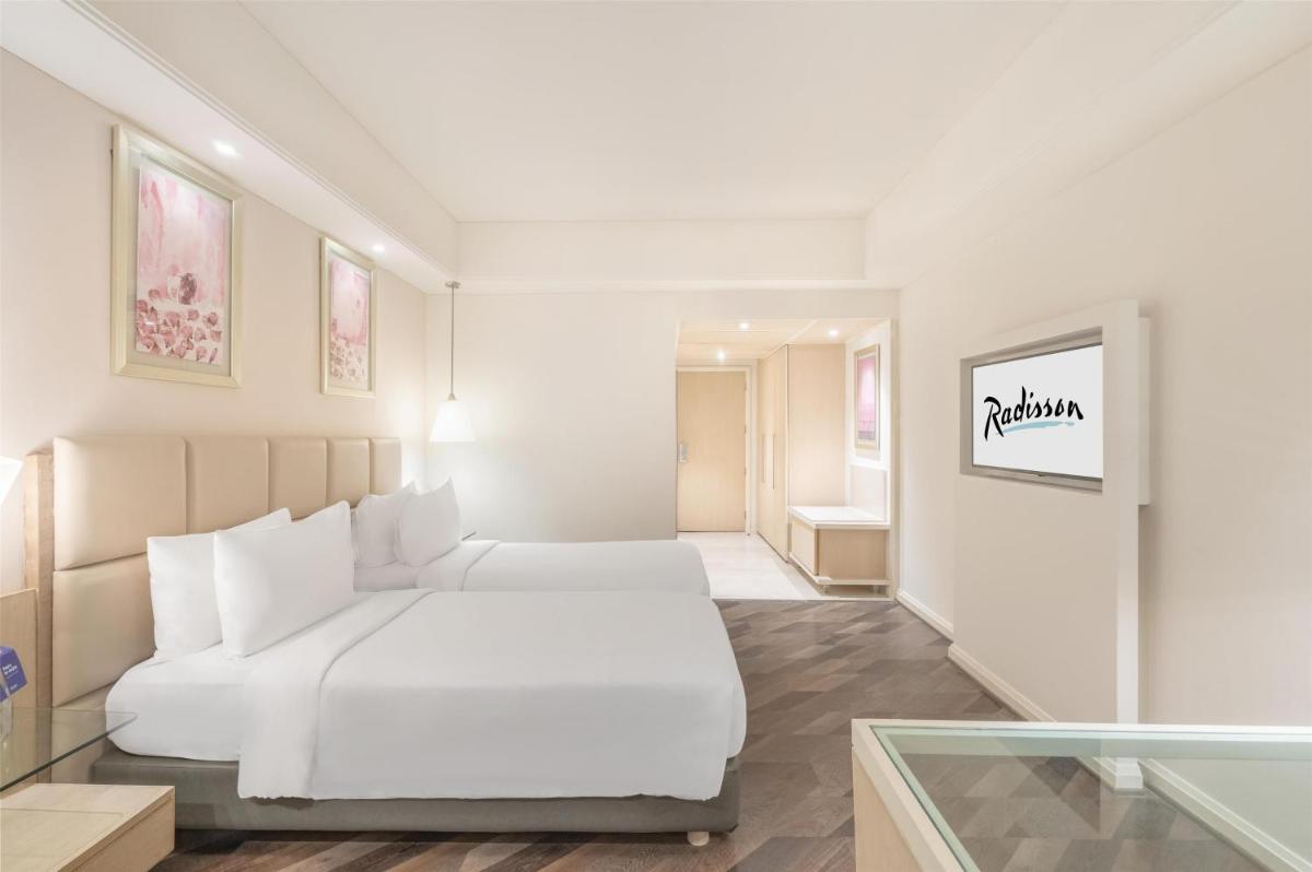 a white bedroom with a white bed and a window at Radisson Hyderabad Hitec City in Hyderabad