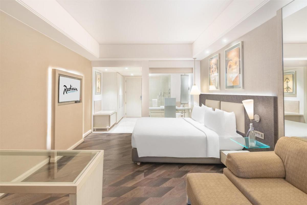a bedroom with a bed and a living room at Radisson Hyderabad Hitec City in Hyderabad
