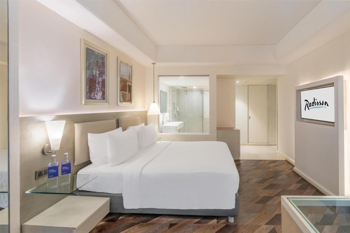 a bedroom with a white bed and a glass table at Radisson Hyderabad Hitec City in Hyderabad