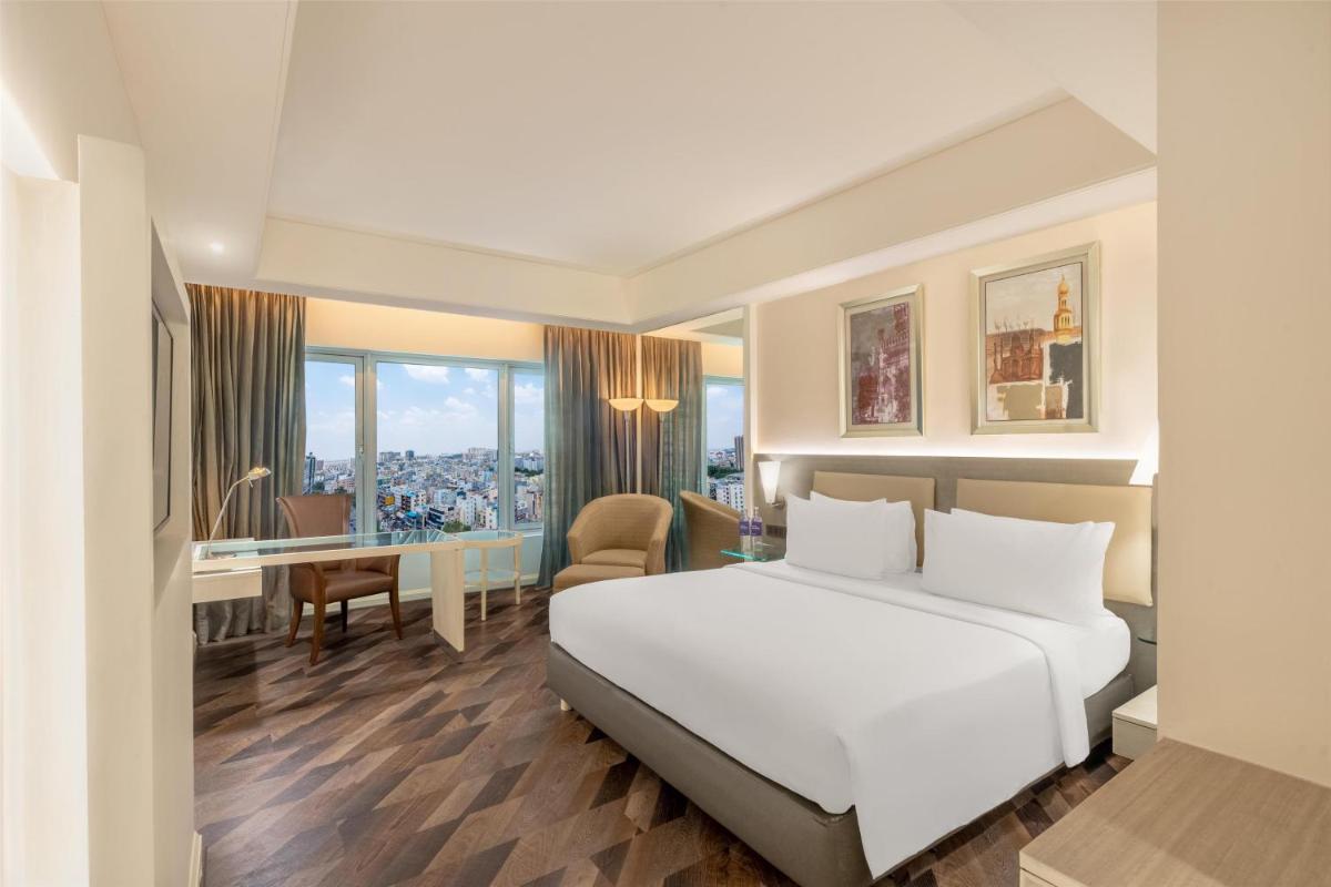 a hotel room with a white bed and a desk at Radisson Hyderabad Hitec City in Hyderabad