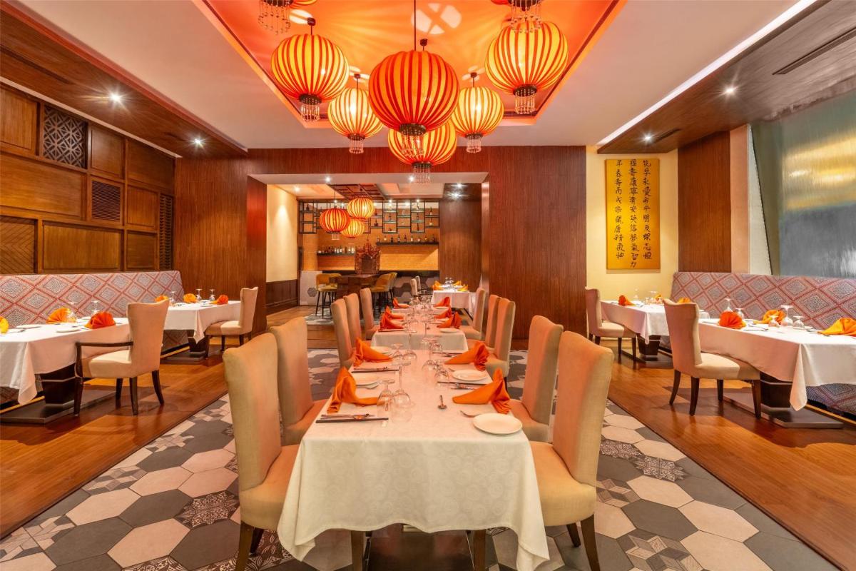 a dining room with tables and chairs and chandeliers at Radisson Hyderabad Hitec City in Hyderabad