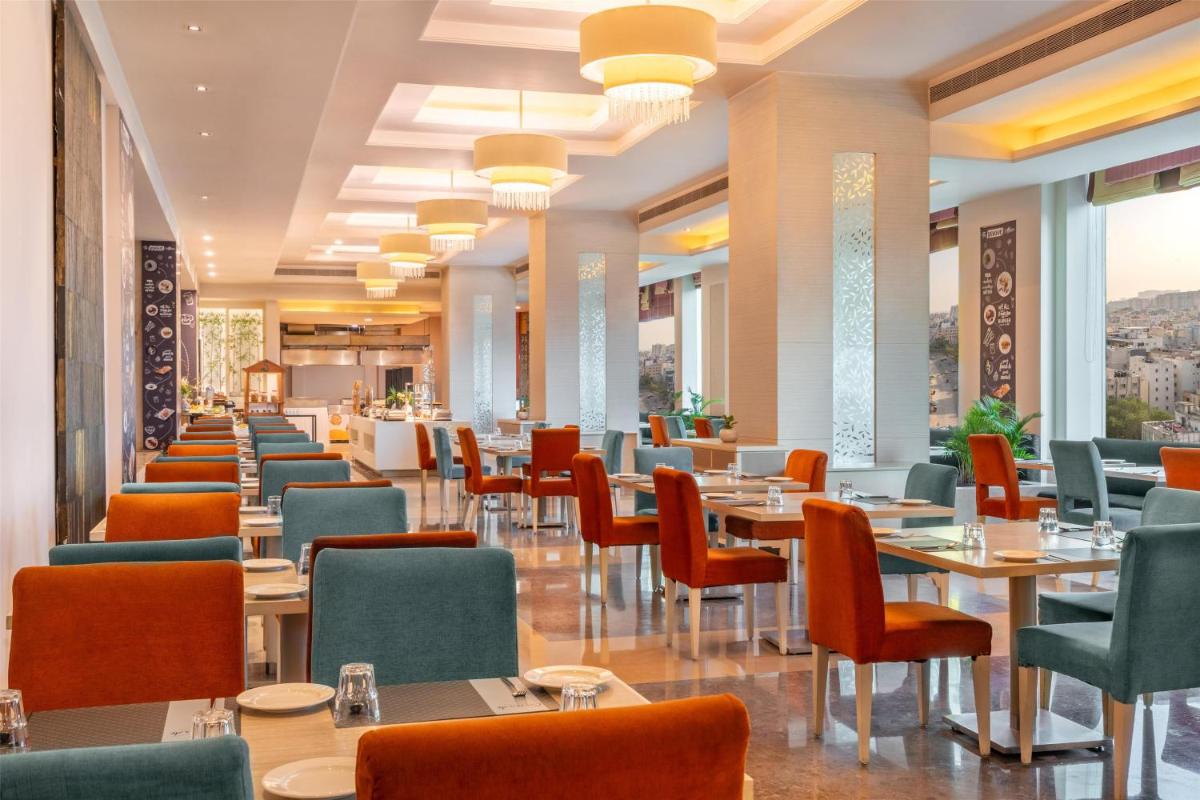 a restaurant with tables and chairs and windows at Radisson Hyderabad Hitec City in Hyderabad