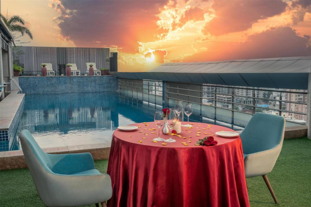 a table with wine glasses on it next to a pool at Radisson Hyderabad Hitec City in Hyderabad
