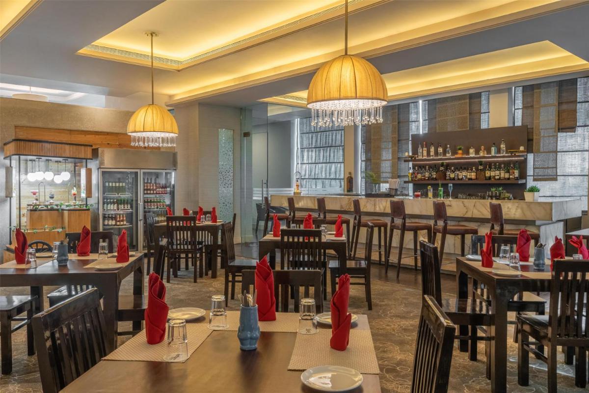 a restaurant with tables and chairs with red napkins at Radisson Hyderabad Hitec City in Hyderabad