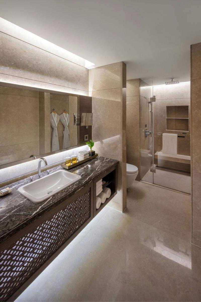 a bathroom with a sink and a toilet and a mirror at JW Marriott Mumbai Sahar Airport in Mumbai
