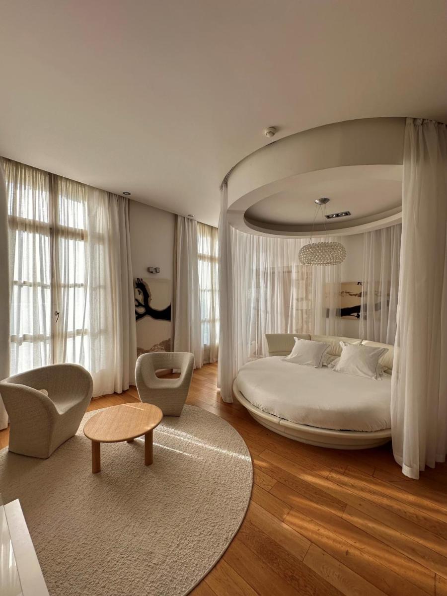 une chambre avec un grand lit blanc et une chaise dans l'établissement Domaine de Verchant & Spa - Relais & Châteaux, à Montpellier