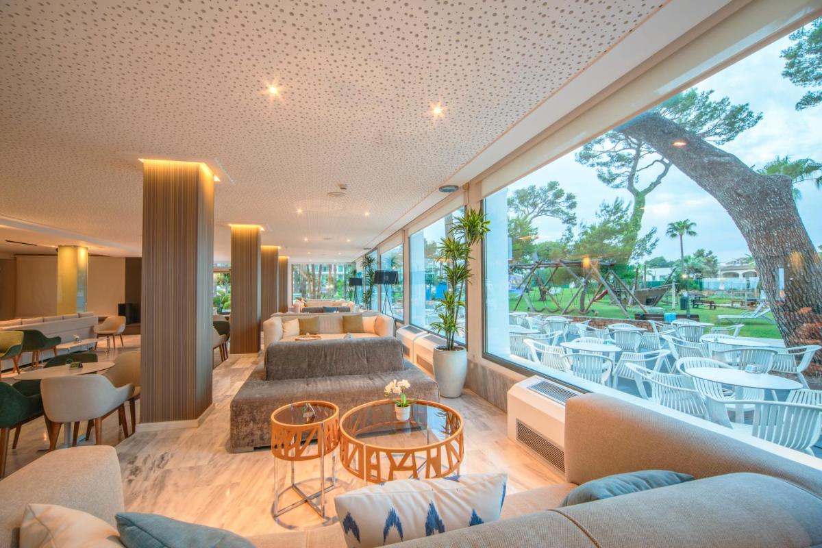 una sala de estar con sofás, mesas y una gran ventana. en Playa Esperanza Resort Affiliated by Meliá, en Playa de Muro 256 fotos más