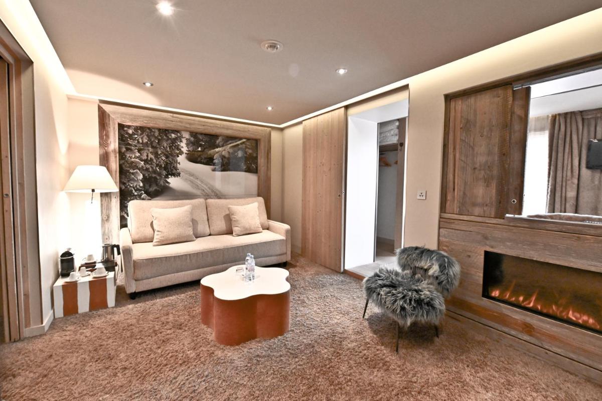 un salon avec un canapé et une cheminée dans l'établissement Hotel Tsanteleina, à Val dʼIsère