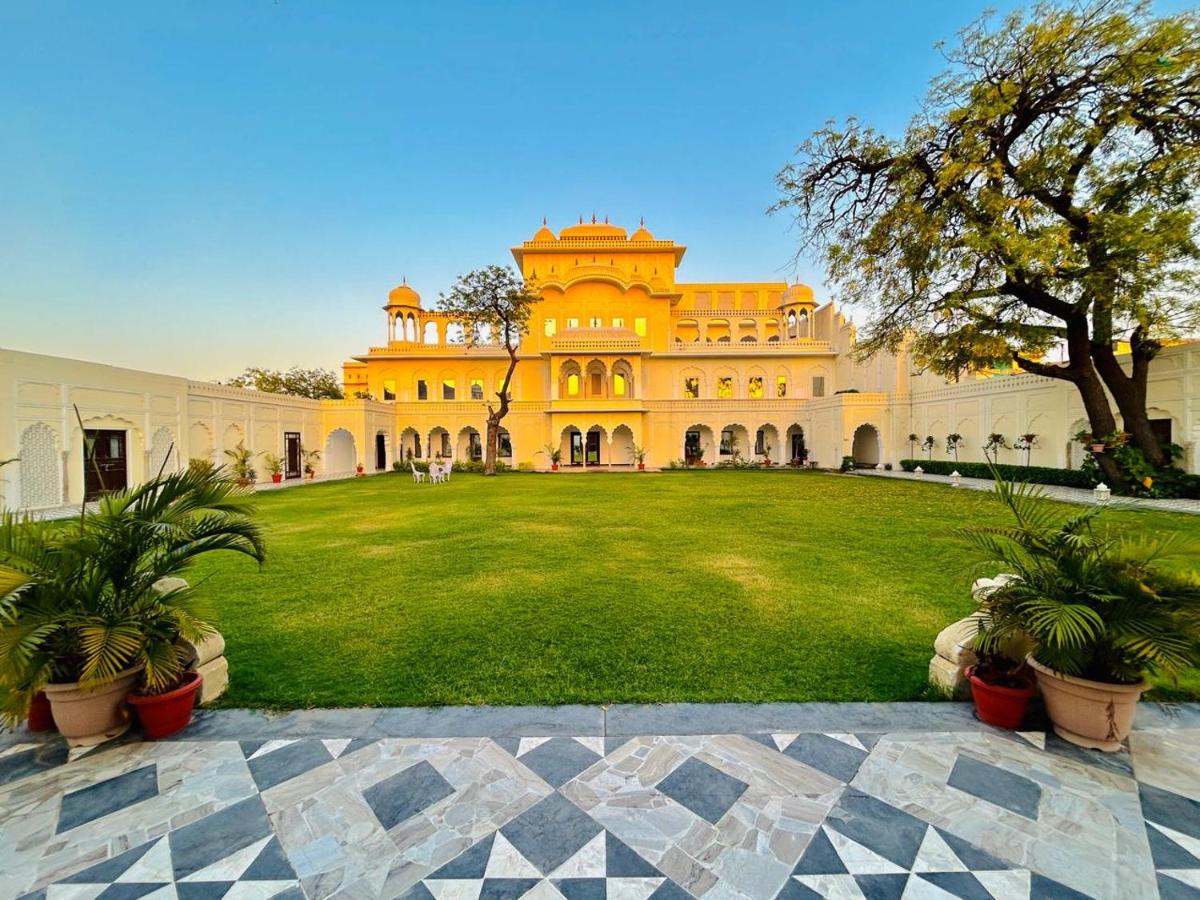 a large yellow building with a grass yard at The Raj Palace (Small Luxury Hotels of the World) in Jaipur