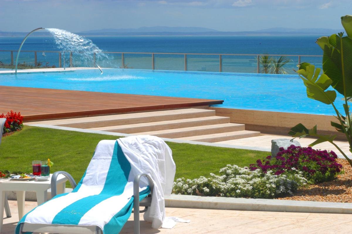 uma piscina com mesa e cadeiras e o oceano em Hotel Cascais Miragem Health & Spa em Cascais