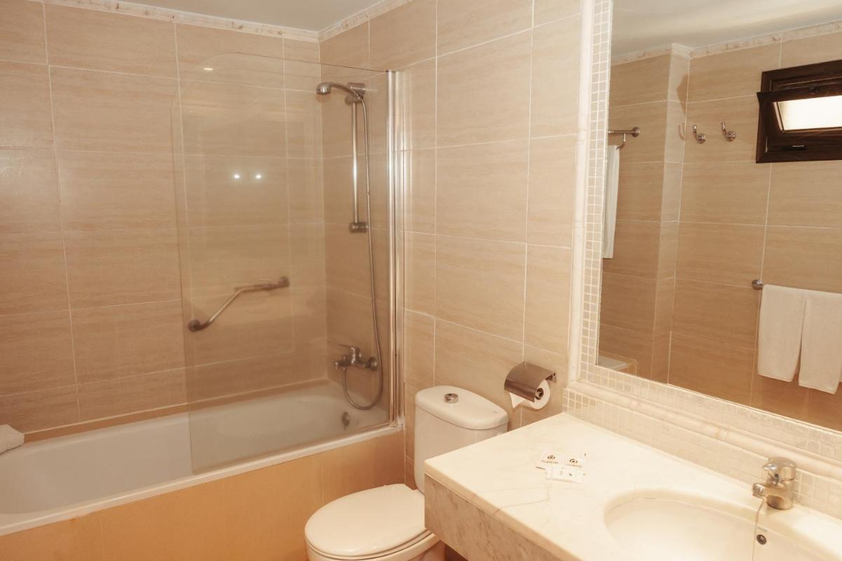 Un baño con inodoro, lavabo y ducha. en Hotel LIVVO Lago Taurito & Aquapark, en Taurito