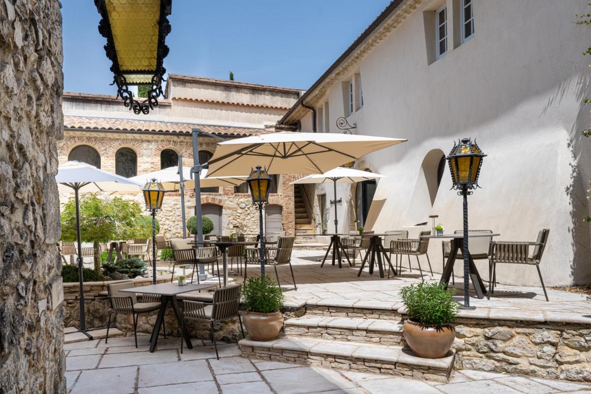 un patio extérieur avec tables, chaises et parasols dans l'établissement Le Domaine Du Colombier, à Malataverne
