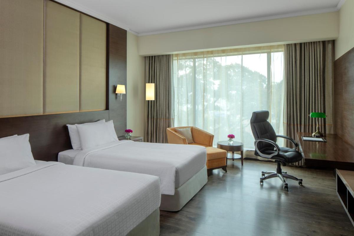 a hotel room with two beds and a chair at Radisson Blu Plaza Hotel Mysore in Mysore