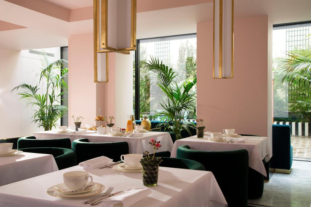 une salle à manger avec des tables blanches et des chaises vertes dans l'établissement Hôtel Saint-Marc, à Paris