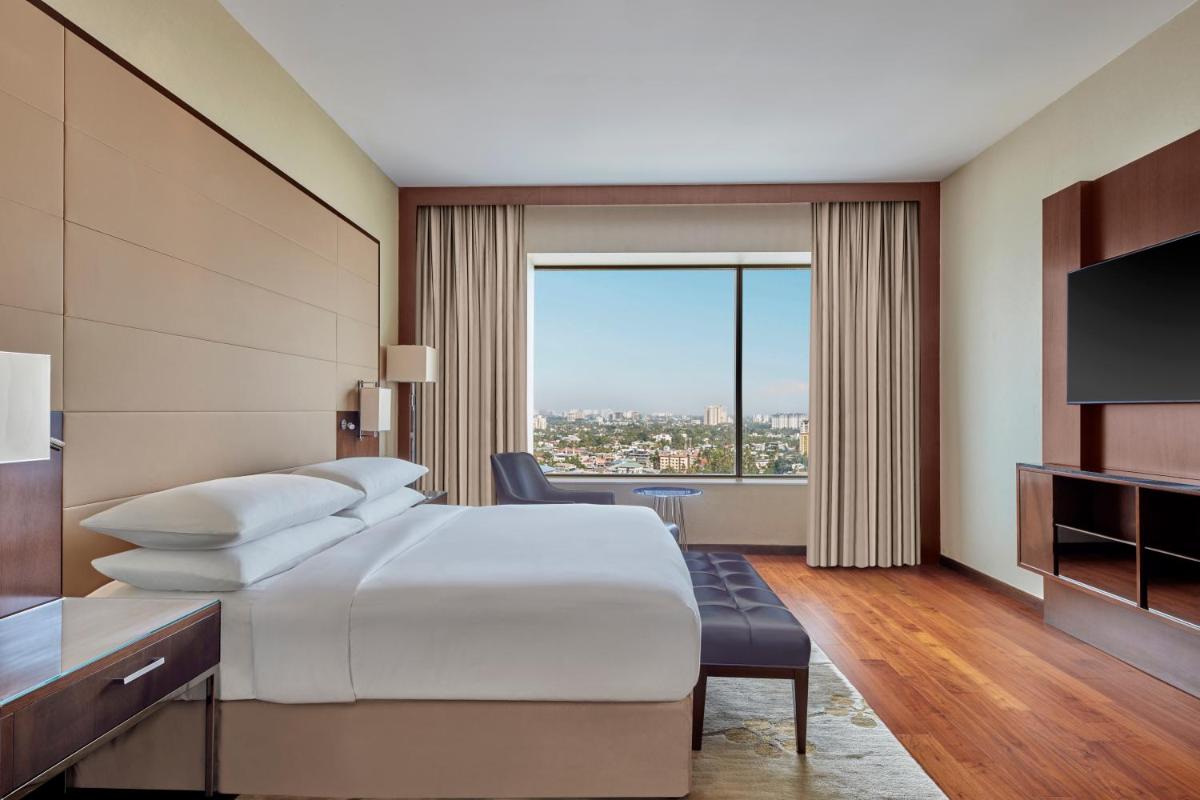 a hotel room with a bed and a television at Kochi Marriott Hotel in Cochin