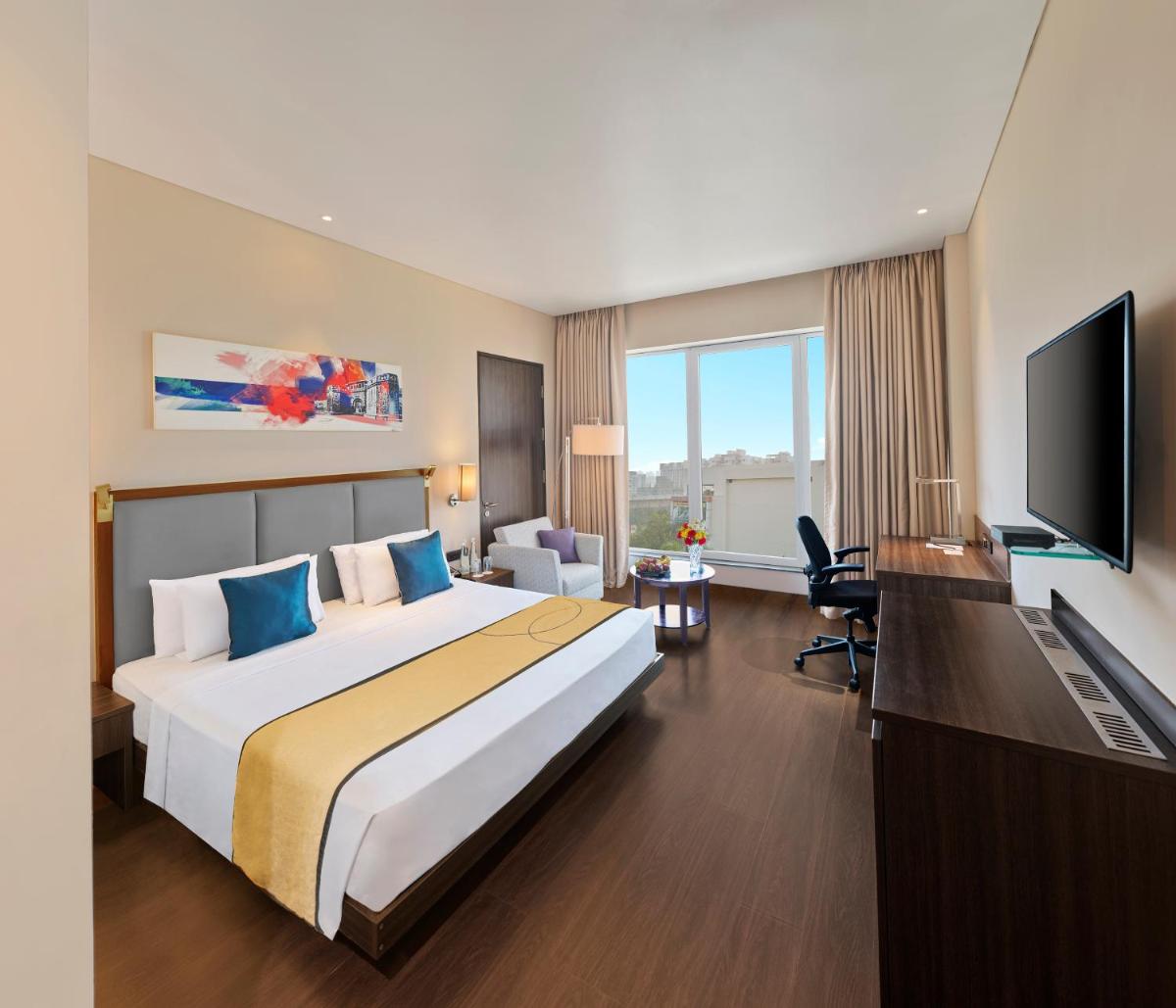 a hotel room with a large bed and a television at Vivanta Pune, Hinjawadi in Pune