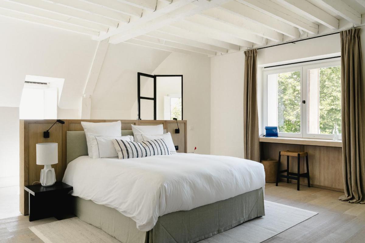 - une chambre blanche avec un grand lit et des fenêtres dans l'établissement Les Hauts de Sancerre, à Sancerre