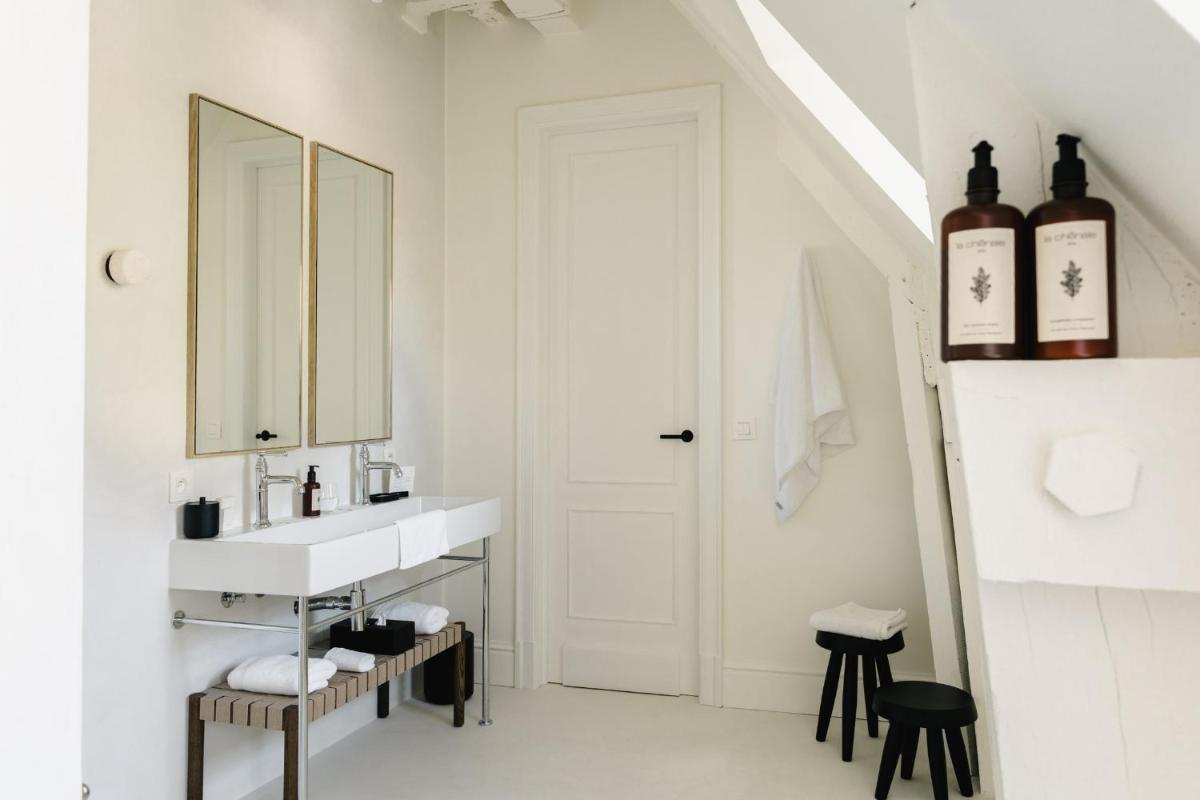 une salle de bain blanche avec un lavabo et un miroir dans l'établissement Les Hauts de Sancerre, à Sancerre 37 autres photos