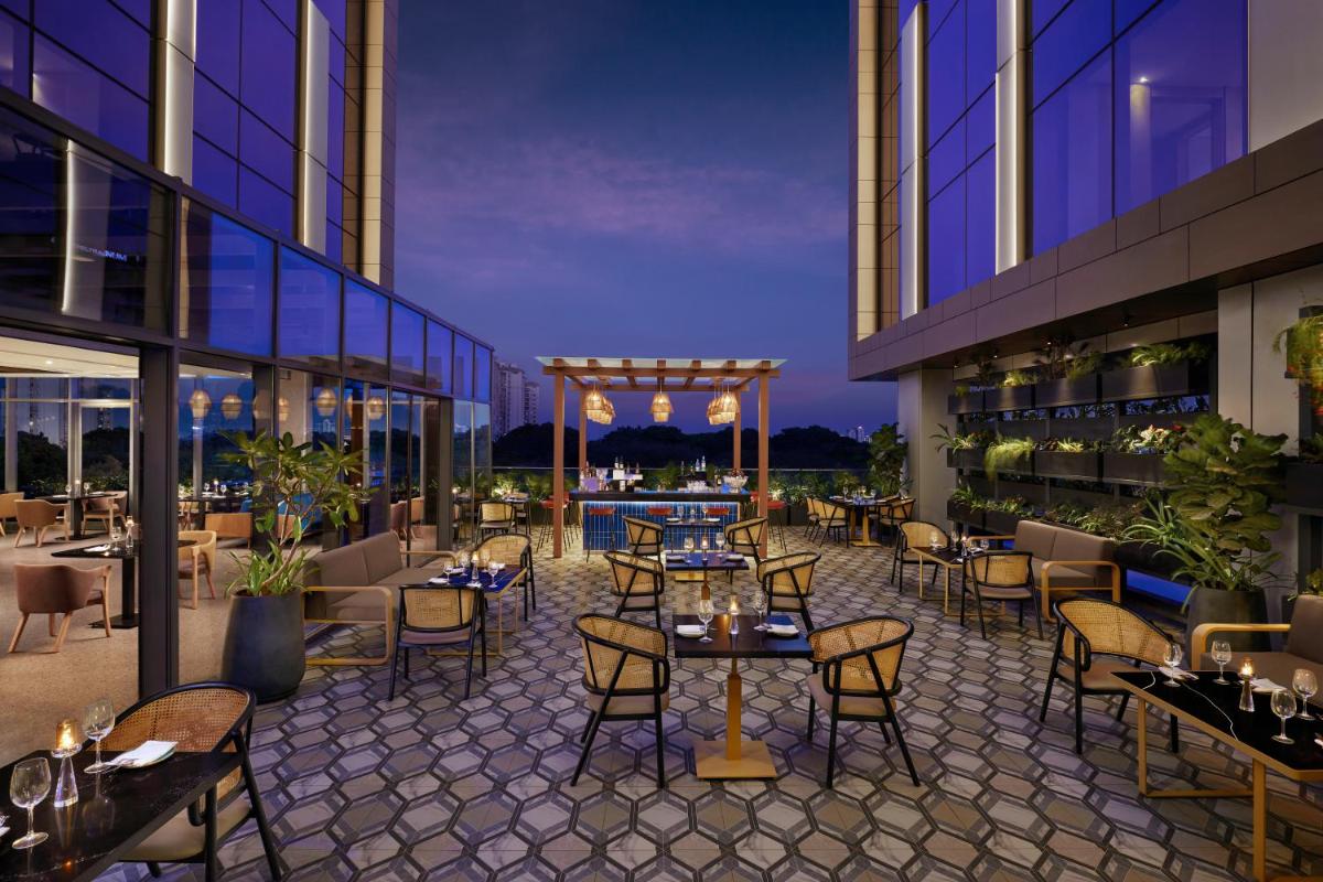 an outdoor patio with tables and chairs on a building at Hyatt Centric Hebbal Bengaluru in Bengaluru