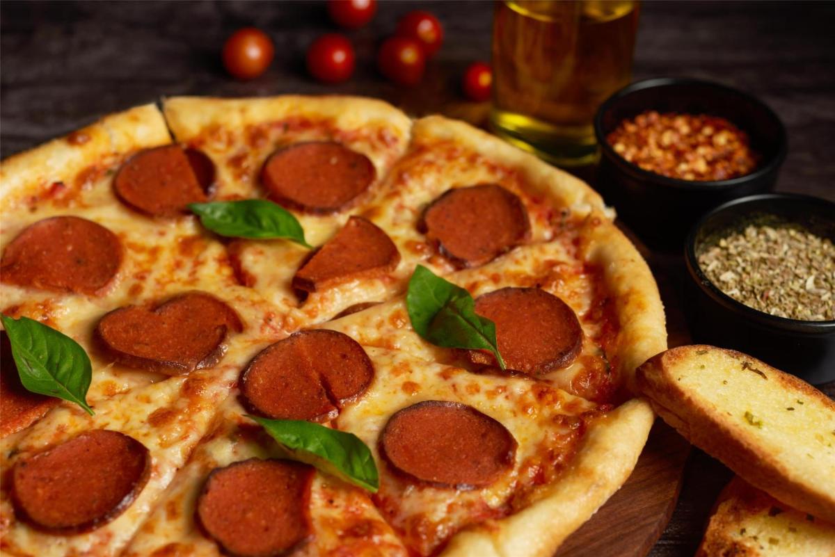 two slices of pepperoni pizza on a wooden table at Radisson Blu Mumbai International Airport in Mumbai two slices of pepperoni pizza on a wooden table at Radisson Blu Mumbai International Airport in Mumbai