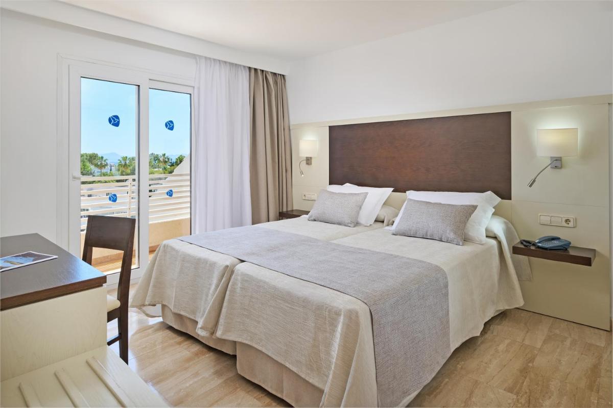 Una habitación de hotel con una cama grande y un balcón. en Grupotel Port D´Alcudia, en Puerto de Alcudia