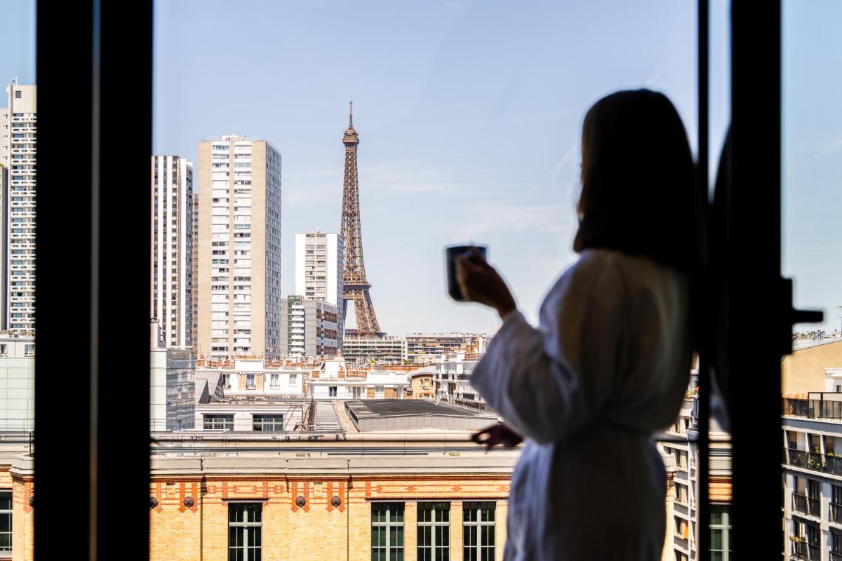une femme prenant une photo de la tour Eiffel dans l'établissement Quinzerie hôtel, à Paris