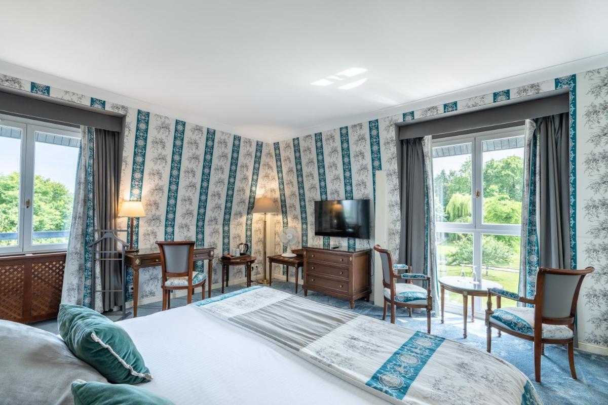 une chambre avec un lit, un bureau et une télévision dans l'établissement Le Manoir De La Poterie & Spa, à Cricquebœuf