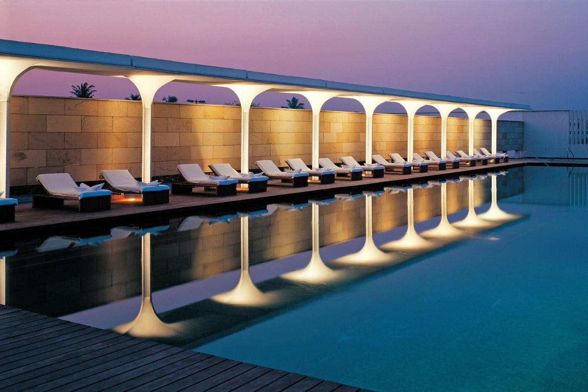 a swimming pool with lounge chairs next to a building at ITC Sonar, a Luxury Collection Hotel, Kolkata in Kolkata