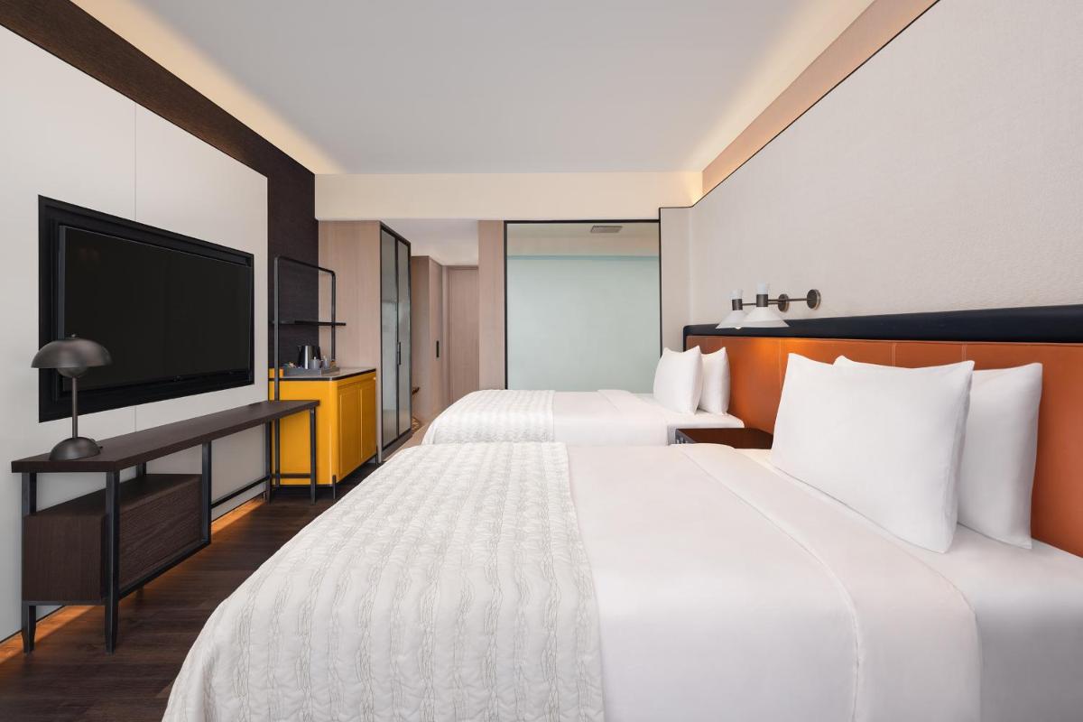 a hotel room with two beds and a flat screen tv at Le Meridien Ahmedabad in Ahmedabad