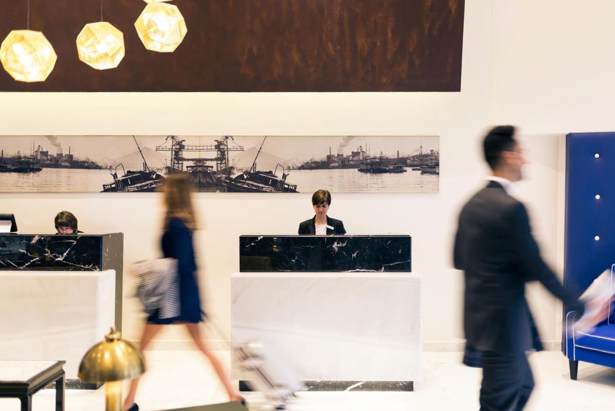 un grupo de personas caminando en una habitación con pinturas en la pared en Hotel Mercure Jardines de Albia, en Bilbao