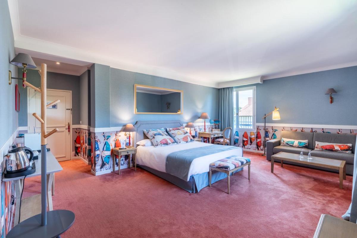 une chambre d'hôtel avec un lit et un canapé dans l'établissement Le Manoir De La Poterie & Spa, à Cricquebœuf