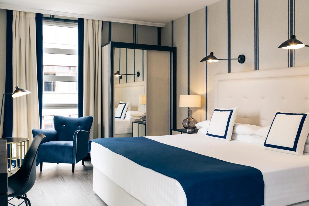 Una habitación de hotel con una cama grande y una silla. en Hotel Mercure Jardines de Albia, en Bilbao