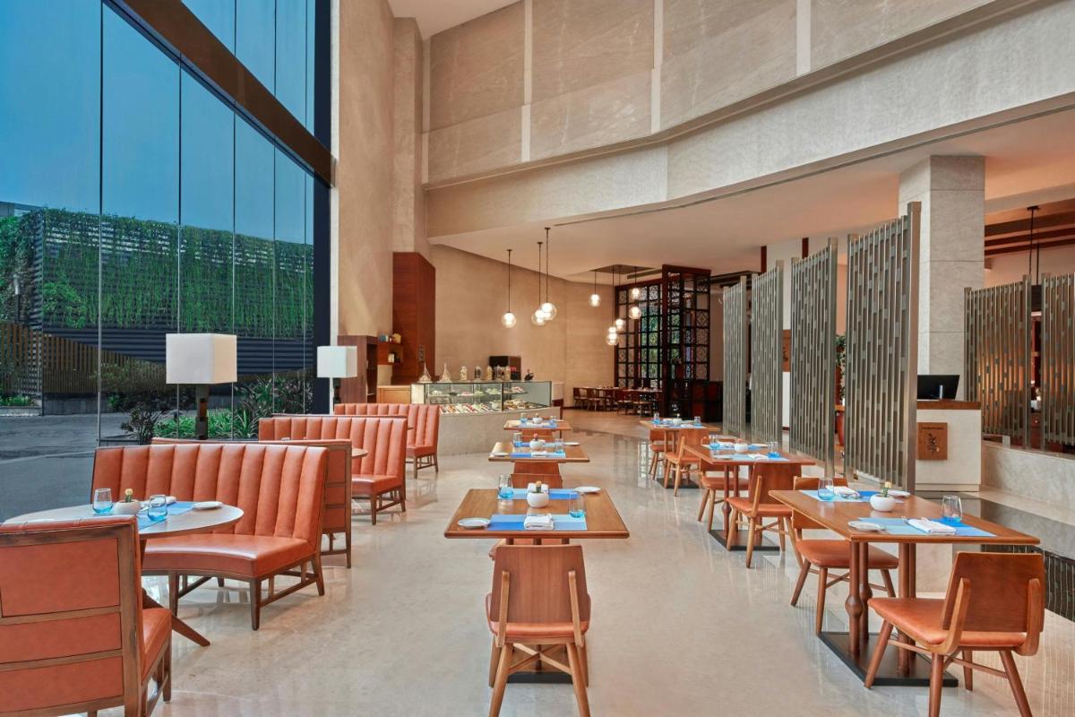 a restaurant with tables and chairs and large windows at Kochi Marriott Hotel in Cochin