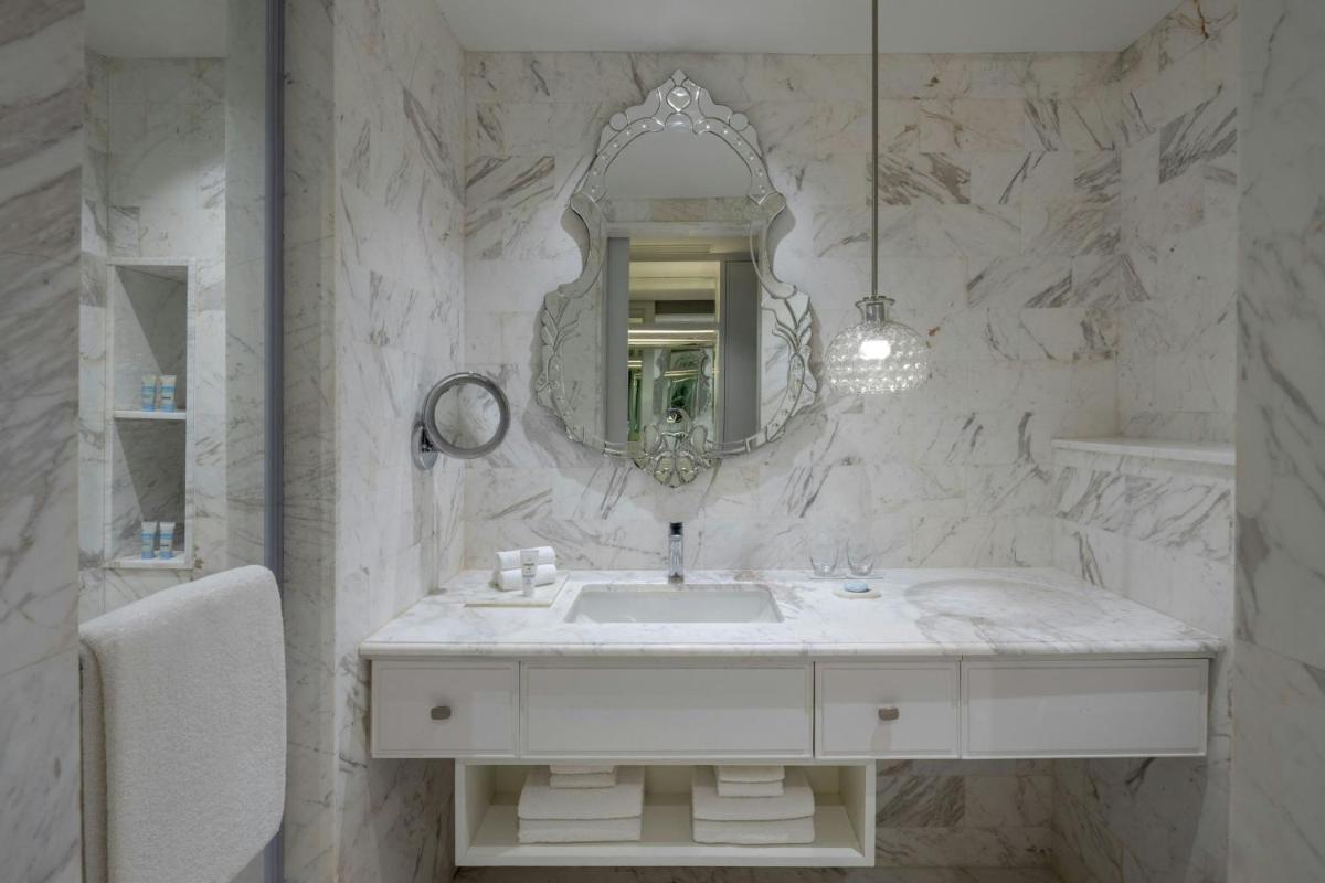 a white bathroom with a sink and a mirror at ITC Windsor, a Luxury Collection Hotel, Bengaluru in Bengaluru a white bathroom with a sink and a mirror at ITC Windsor, a Luxury Collection Hotel, Bengaluru in Bengaluru