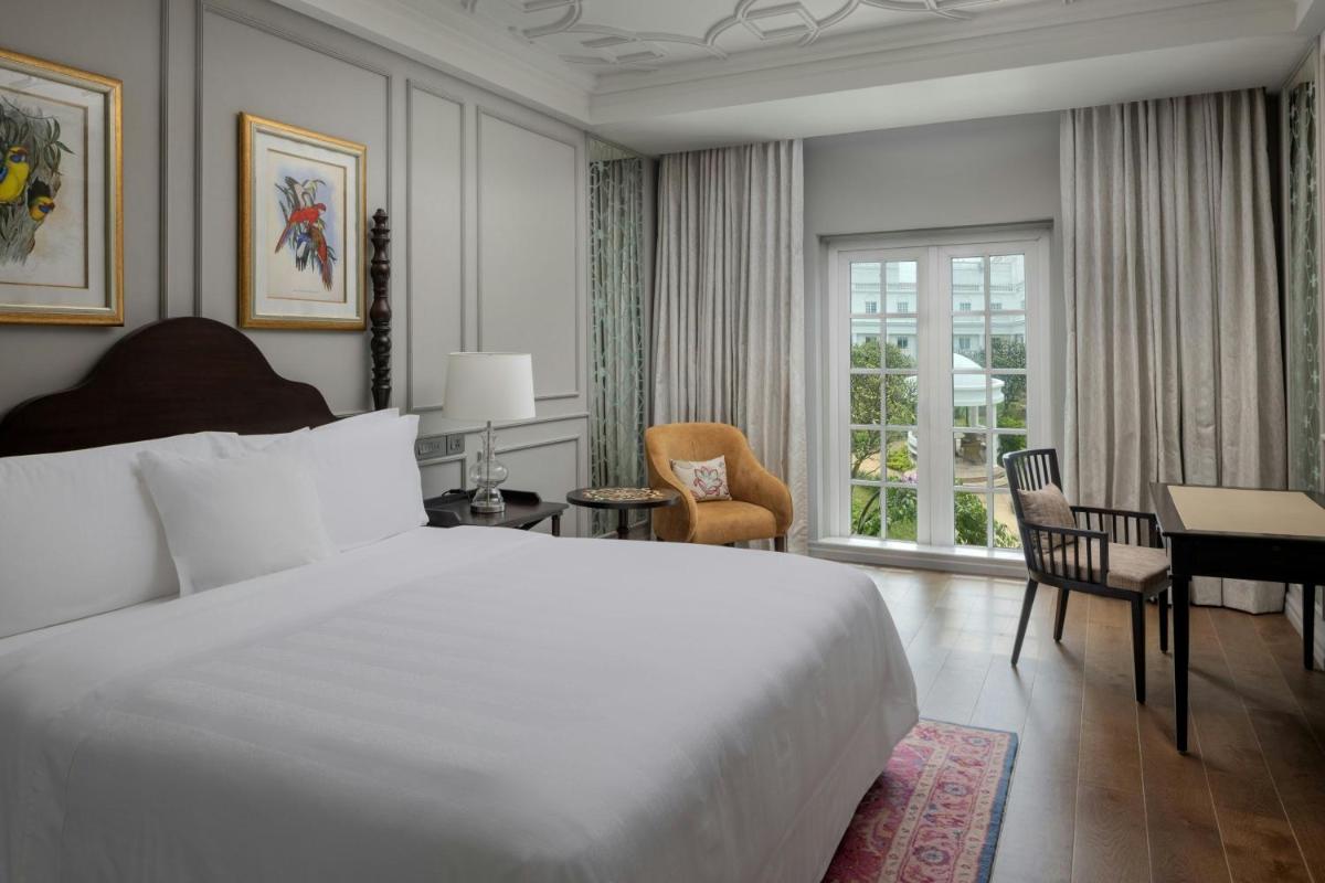 a bedroom with a large white bed and a desk at ITC Windsor, a Luxury Collection Hotel, Bengaluru in Bengaluru a bedroom with a large white bed and a desk at ITC Windsor, a Luxury Collection Hotel, Bengaluru in Bengaluru