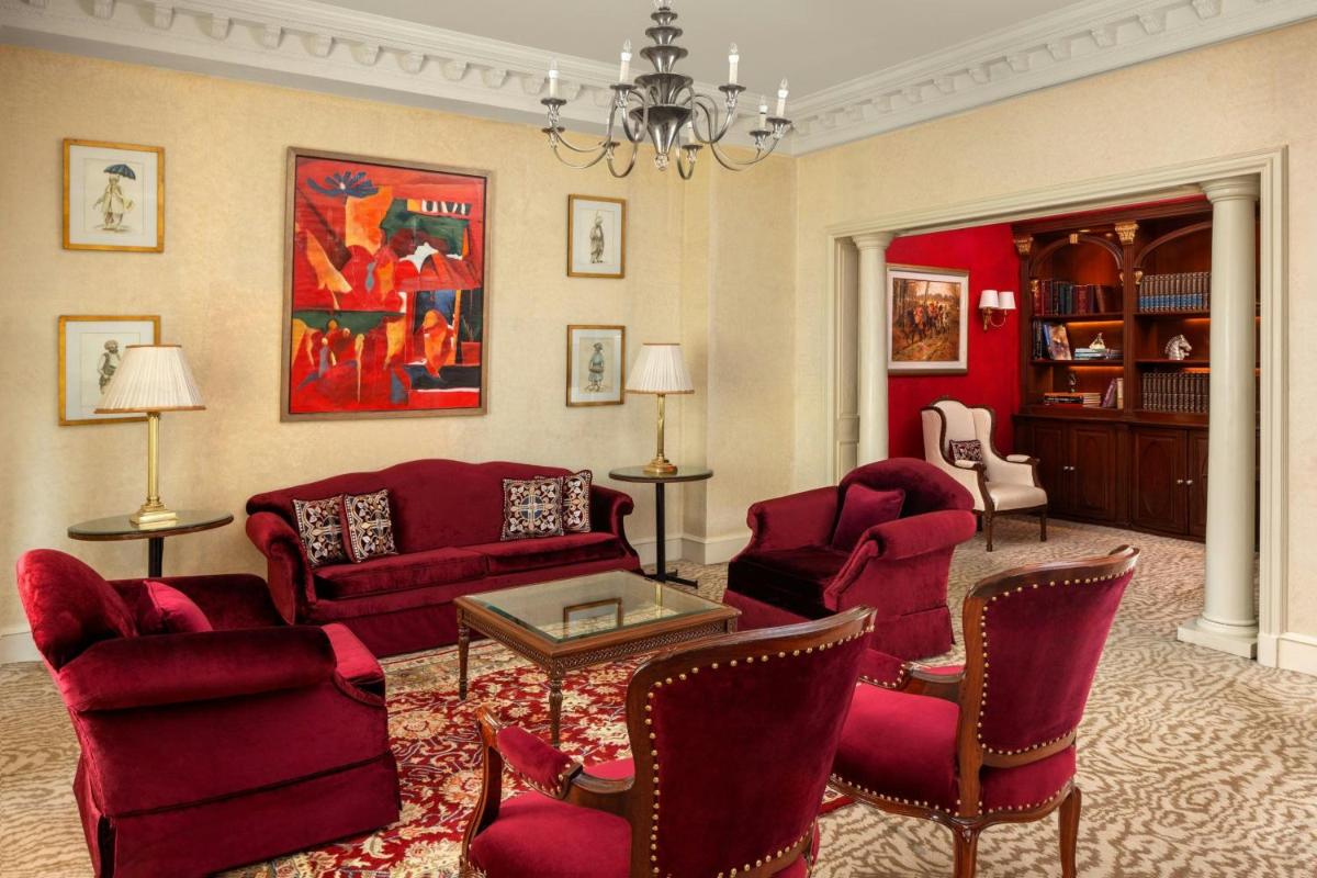 a living room with red furniture and a chandelier at ITC Windsor, a Luxury Collection Hotel, Bengaluru in Bengaluru a living room with red furniture and a chandelier at ITC Windsor, a Luxury Collection Hotel, Bengaluru in Bengaluru