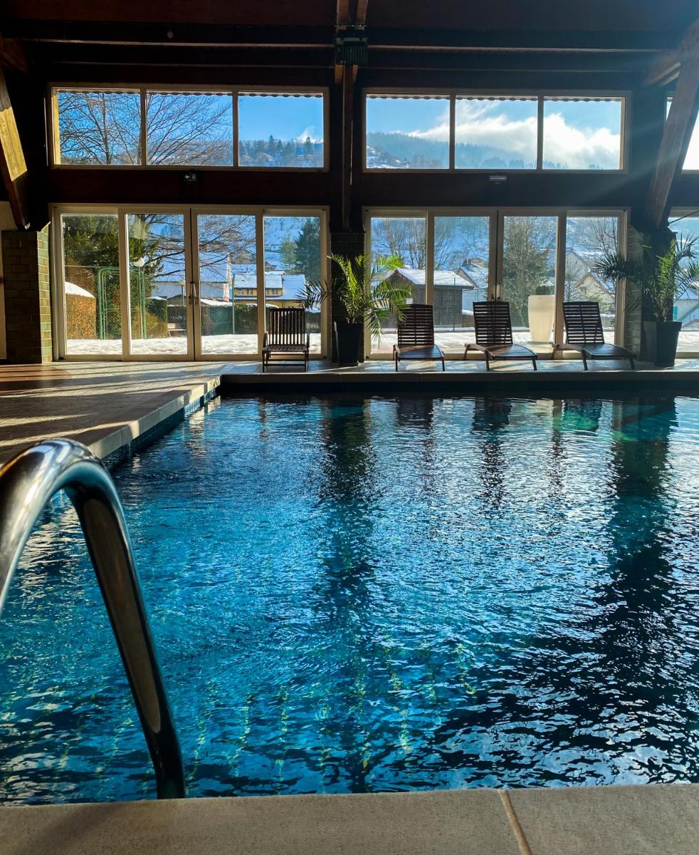 une piscine avec des chaises longues dans un bâtiment dans l'établissement Résidence Les Vallées Labellemontagne, à La Bresse