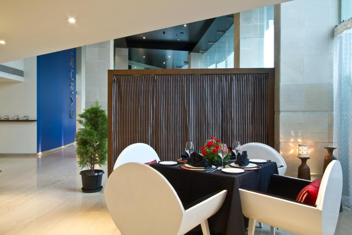 a dining room with a black table and white chairs at Svenska Design Hotel, Electronic City, Bangalore in Bengaluru a dining room with a black table and white chairs at Svenska Design Hotel, Electronic City, Bangalore in Bengaluru