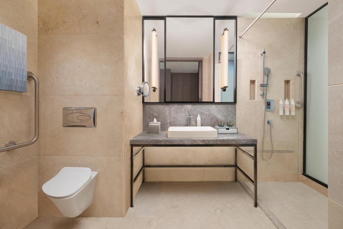 a bathroom with a sink and a toilet and a mirror at Le Meridien Ahmedabad in Ahmedabad