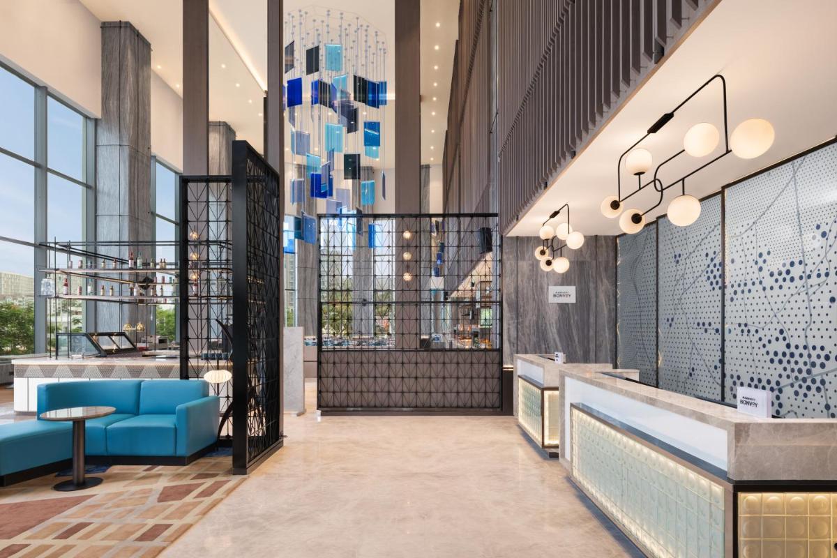 a lobby with blue furniture and large windows at Le Meridien Ahmedabad in Ahmedabad