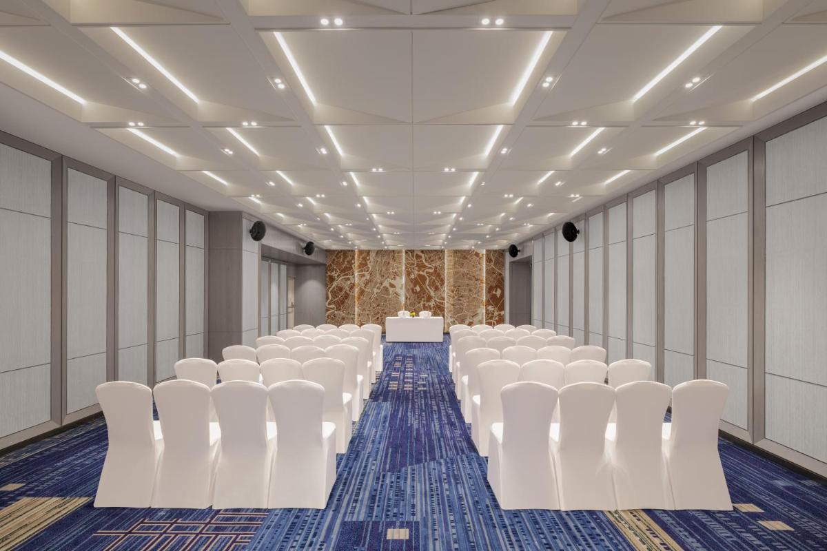 an empty room with white chairs and a table at Le Meridien Ahmedabad in Ahmedabad