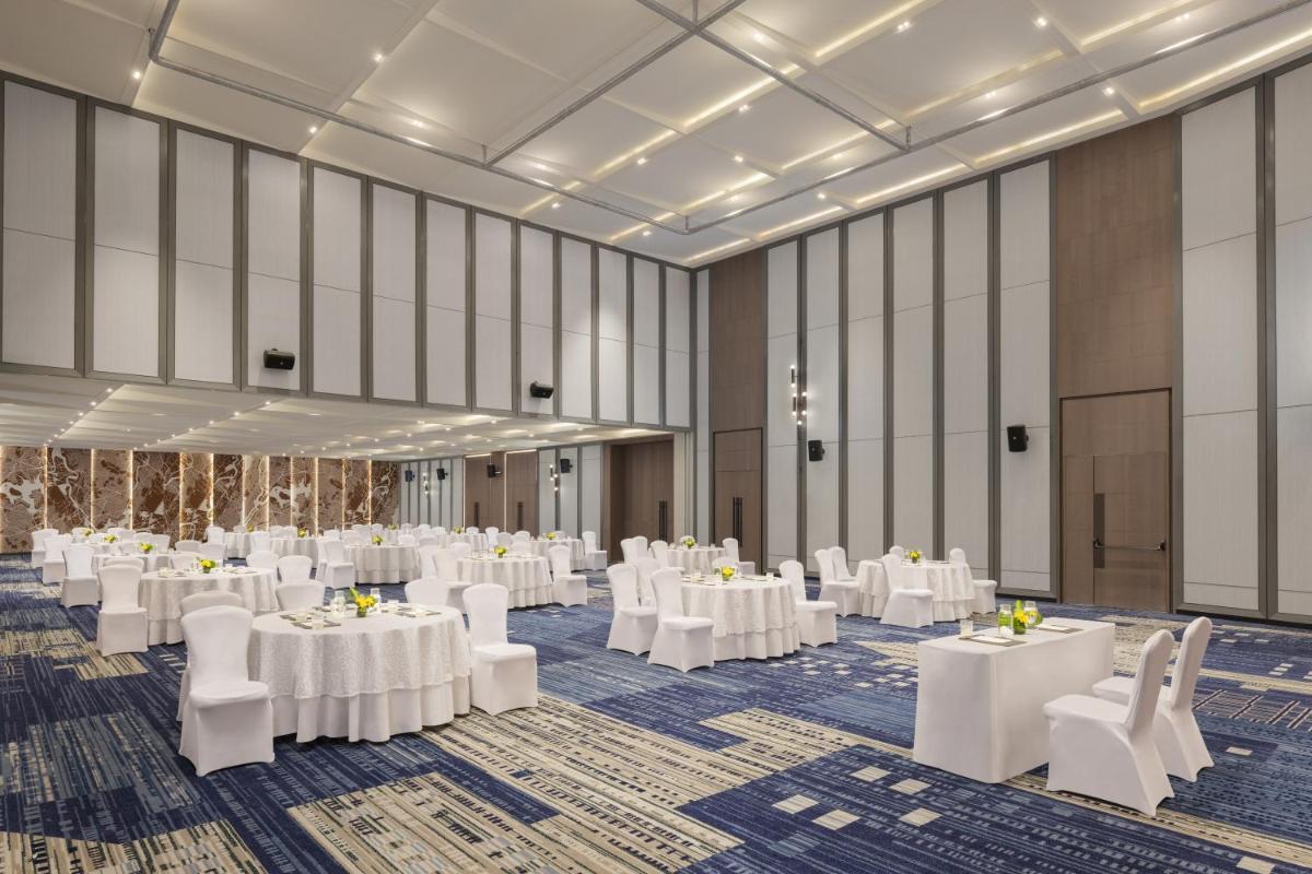 a banquet hall with white tables and white chairs at Le Meridien Ahmedabad in Ahmedabad